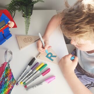 Child colouring in wooden ply bunting with markers