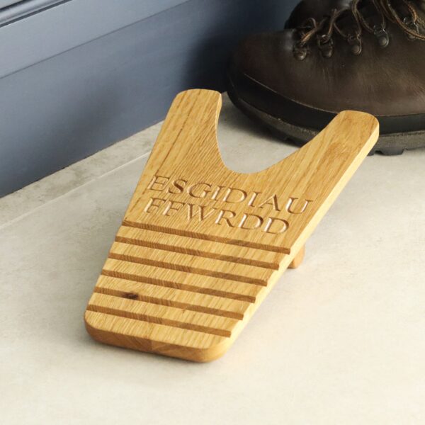 Boot jack with 'ESGIDIAU FFWRDD' engraved